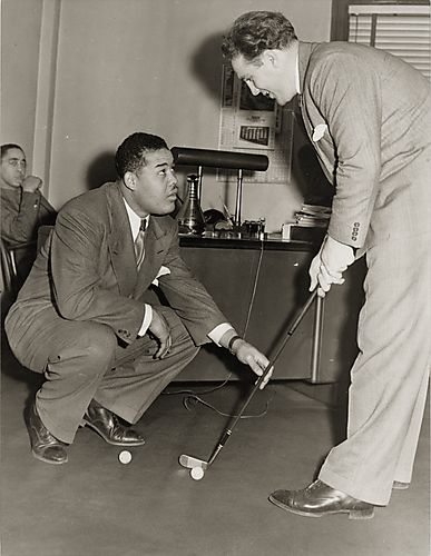 Boxers Joe Louis and Billy Conn practice putting in Pittsburgh Courier offices before their fight