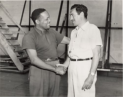 Two men shaking hands, one with whistle and cigarette