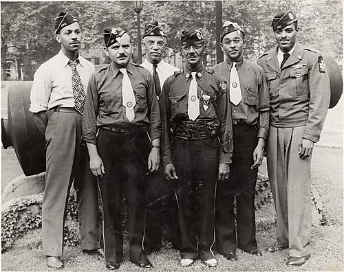 Six veterans posing in front of a cannon