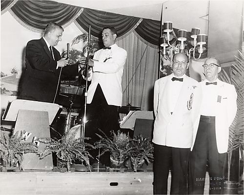 Judge Henry Smith, Byron Peters, and Harry Washington in tuxedos, with a fourth man, and bandstand