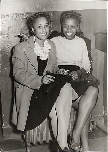 (Two women sitting on radiator, both with cigarettes)