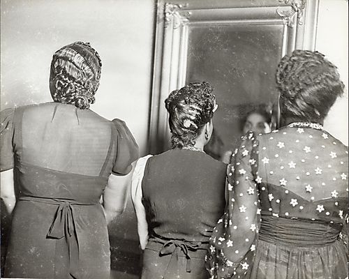 Three women facing a mirror