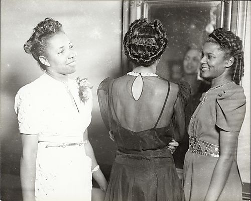 Three women, with one in center facing a mirror