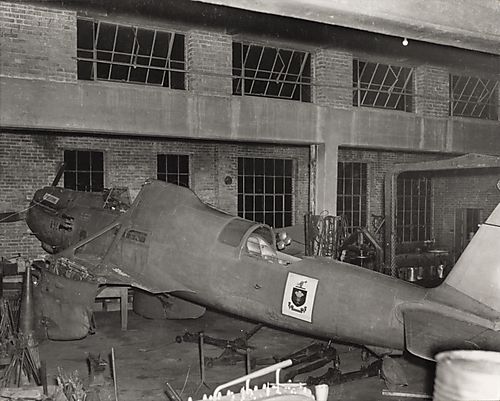 Wingless single-engine airplane with coat of arms on fuselage in workshop
