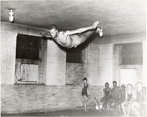 Diver in air with swimmers, possibly at Centre Avenue YMCA, Hill District