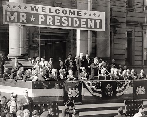 President John F. Kennedy addressing crowd in front of large stone municipal building with doric columns
