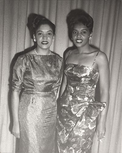Two women in evening dress, one holding cigarette