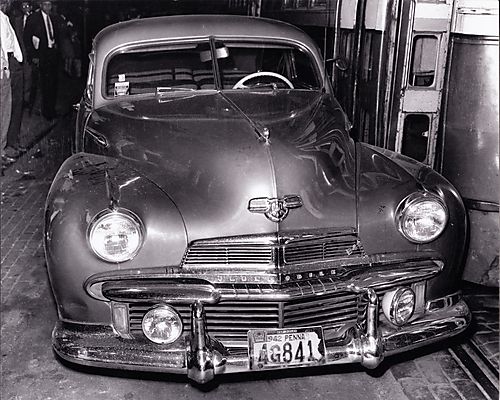 Oldsmobile car next to streetcar, at night