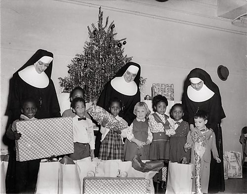 Nuns with children and gifts before Christmas tree