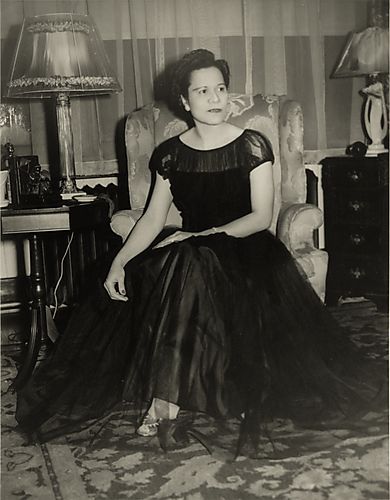 Julia, neighbor of the Harris family, sitting on wing chair and wearing evening gown