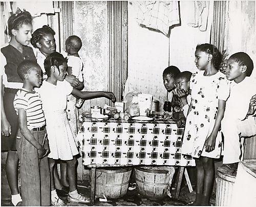 Woman and seven children at kitchen table with groceries