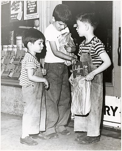 Three boys with groceries and box of Chiffon soap outside a grocery store
