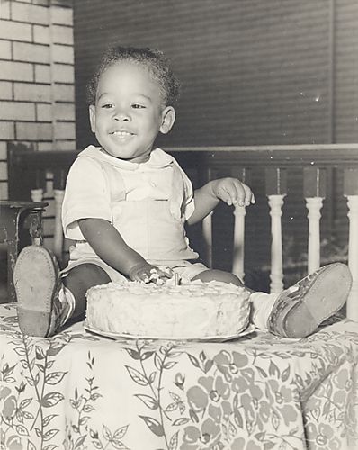 Portrait of Vann Harris as a baby with hand in cake