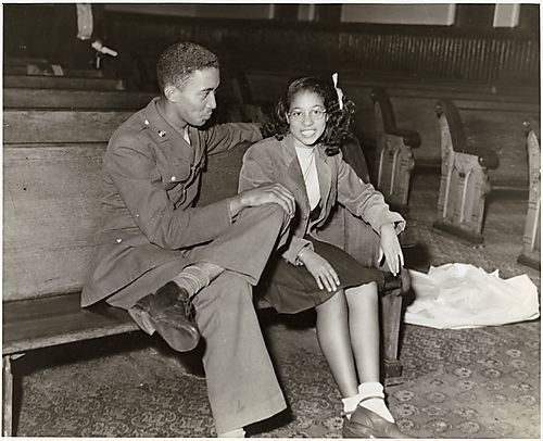 Young man in uniform with young woman on bench
