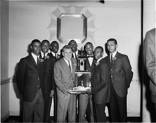 Group portrait of Schenley High School 1966 state championship basketball players holding trophy, including from left to right: Jacob H. Williams, Jr., Montel Brundage, Marvin Snowden, coach Willard Fisher, Kenneth Kenny" Durrett, James "Jimmy" Prince, Ed