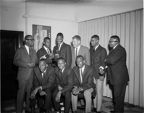 Group portrait of men and Schenley High School 1966 state champion basketball players, including from left to right seated: Kenneth Kenny" Durrett, Montel Brundage, Marvin Snowden; standing: John Turner, Edward "Petey" Gibson holding two trophies, James P