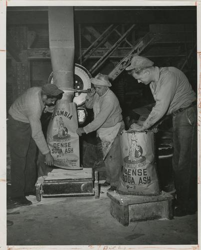 Employees pouring Dense Soda Ash into bags