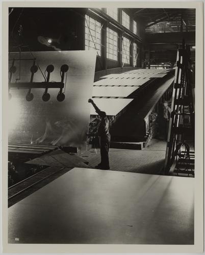 Employee removing plate glass from conveyor belt