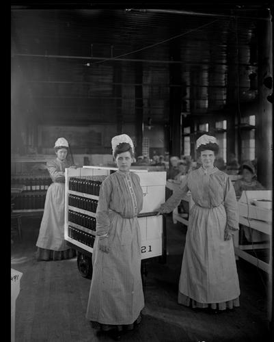 Women using rolling cart to transport bottles