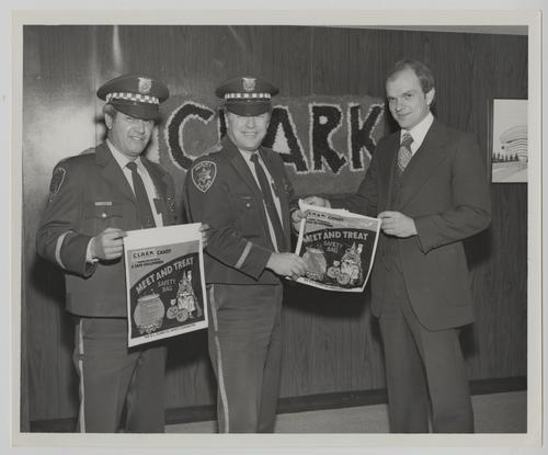 Pittsburgh Police Officers and D. L. Clark Company Executive posing with Halloween "Meet and Treat" Safety Bags