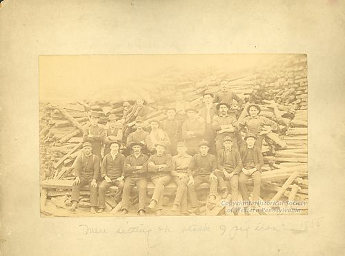 Men sitting on stack of Pig Iron